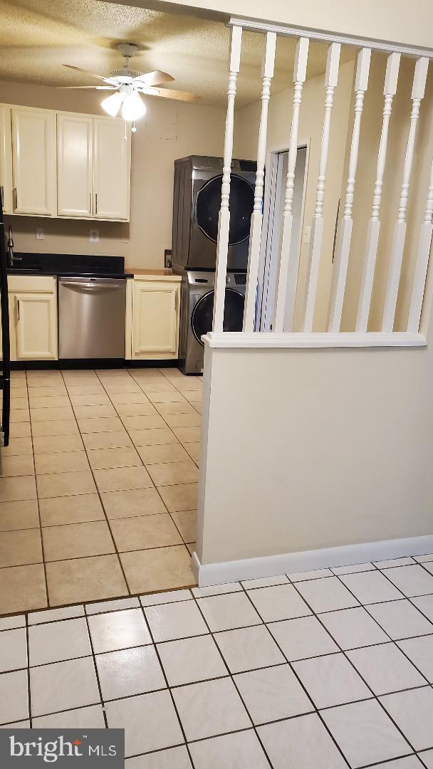 3705 S George Mason Dr Unit 1311, Falls Church, VA 22041 - kitchen featuring stacked washer and clothes dryer, stainless steel dishwasher, light tile patterned flooring, ceiling fan, and white cabinets
