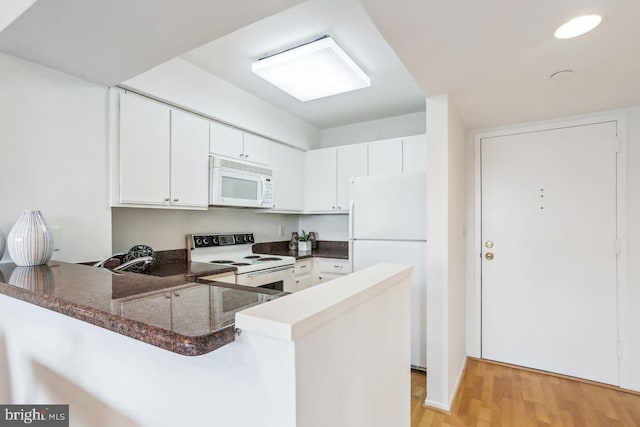 1401 17th St NW Unit 610, Washington, DC 20036 - kitchen featuring white appliances, a peninsula, light wood-type flooring, white cabinetry, and dark stone counters