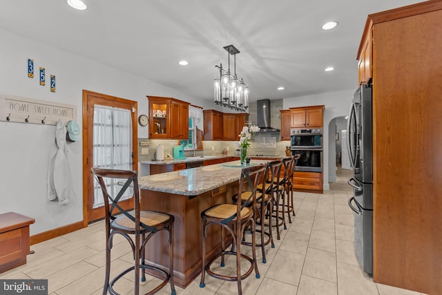 352 Concord Rd, Glen Mills, PA 19342 - kitchen featuring wall chimney range hood, stainless steel appliances, brown cabinetry, a center island, and recessed lighting