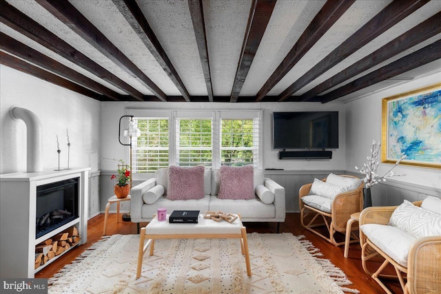 67 W Ferry St, New Hope, PA 18938 - living room featuring beamed ceiling, wood finished floors, a glass covered fireplace, and a wainscoted wall