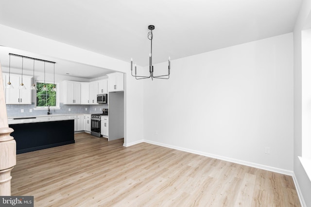 4913 S Broad St, Hamilton, NJ 08620 - kitchen featuring stainless steel appliances, a chandelier, light wood-style floors, light countertops, and backsplash
