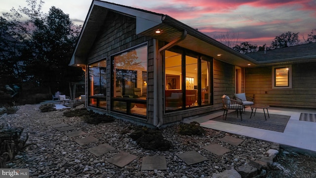302 Fox Run Rd, Wardensville, WV 26851 - back of property at dusk featuring a patio and a sunroom