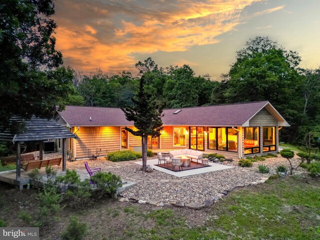 302 Fox Run Rd, Wardensville, WV 26851 - back of property at dusk with an outdoor living space, a patio area, and a sunroom