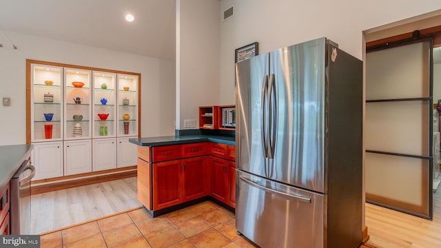 302 Fox Run Rd, Wardensville, WV 26851 - kitchen with freestanding refrigerator, dark countertops, light wood-style floors, reddish brown cabinets, and a peninsula