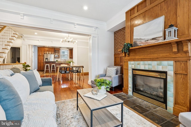 1013 S Decker Ave, Baltimore, MD 21224 - living room featuring stairway, crown molding, a tile fireplace, a chandelier, and recessed lighting