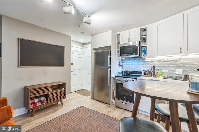 459 Massachusetts Ave NW Unit B1, Washington, DC 20001 - kitchen with stainless steel appliances, white cabinetry, light wood-type flooring, decorative backsplash, and rail lighting