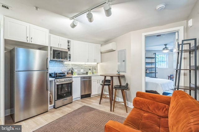 459 Massachusetts Ave NW Unit B1, Washington, DC 20001 - kitchen with stainless steel appliances, electric panel, a wall unit AC, white cabinetry, and light wood-type flooring