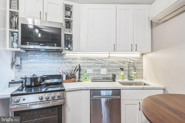 459 Massachusetts Ave NW Unit B1, Washington, DC 20001 - kitchen featuring appliances with stainless steel finishes, a wall mounted air conditioner, white cabinetry, tasteful backsplash, and light stone countertops