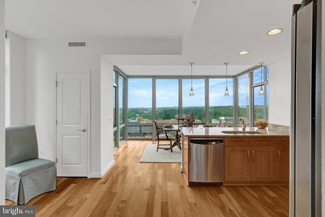 11990 Market St Unit 907, Reston, VA 20190 - kitchen with stainless steel appliances, light wood-style floors, expansive windows, brown cabinetry, and hanging light fixtures