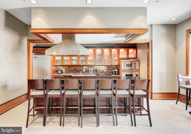 11990 Market St Unit 907, Reston, VA 20190 - kitchen featuring island exhaust hood, stainless steel appliances, tasteful backsplash, a breakfast bar, and recessed lighting