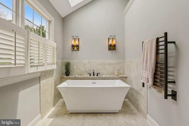 660 Casey Ln, West Chester, PA 19382 - bathroom featuring a towel warmer, a freestanding tub, tile walls, a skylight, and tile patterned floors