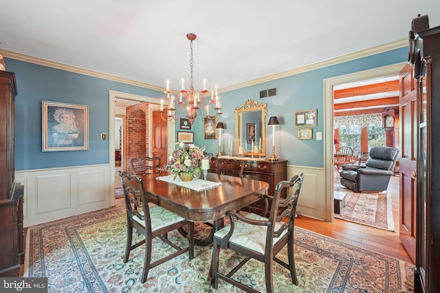 4250 Fretz Mill Rd, New Hope, PA 18938 - dining area featuring a chandelier, light wood-style flooring, a wainscoted wall, crown molding, and a decorative wall