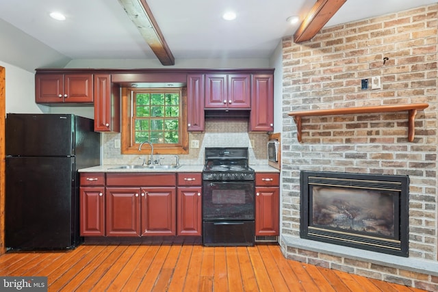 4250 Fretz Mill Rd, New Hope, PA 18938 - kitchen featuring black appliances, light wood-style flooring, decorative backsplash, light stone countertops, and a brick fireplace