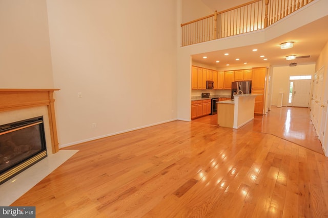 8804 Shining Oceans Way Unit 53, Columbia, MD 21045 - unfurnished living room featuring light wood-type flooring, a fireplace with flush hearth, a high ceiling, and recessed lighting