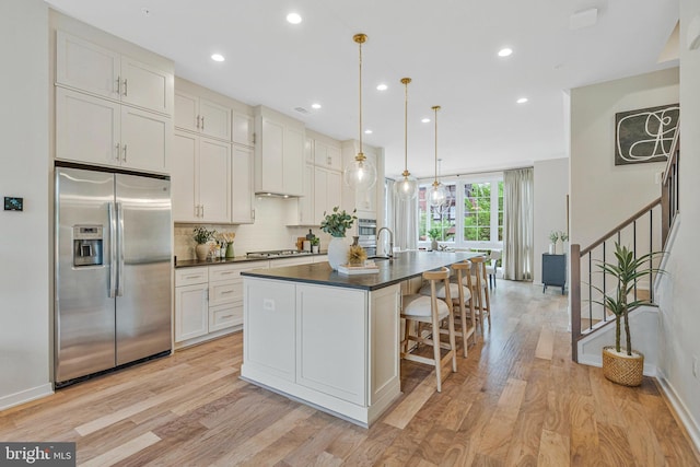 11724 Paysons Way, Reston, VA 20191 - kitchen with stainless steel appliances, dark countertops, light wood-style floors, a center island with sink, and backsplash