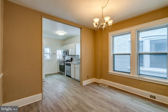 589 N Plum St, Lancaster, PA 17602 - kitchen featuring stainless steel appliances, a chandelier, light wood-style floors, white cabinets, and light countertops