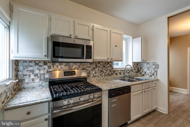 589 N Plum St, Lancaster, PA 17602 - kitchen featuring stainless steel appliances, decorative backsplash, light wood-style flooring, and white cabinetry
