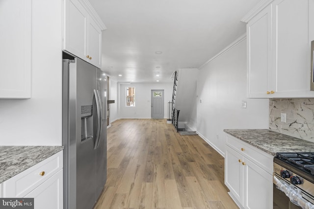 913 E Sanger St, Philadelphia, PA 19124 - kitchen featuring appliances with stainless steel finishes, white cabinetry, tasteful backsplash, light wood-style floors, and light stone countertops