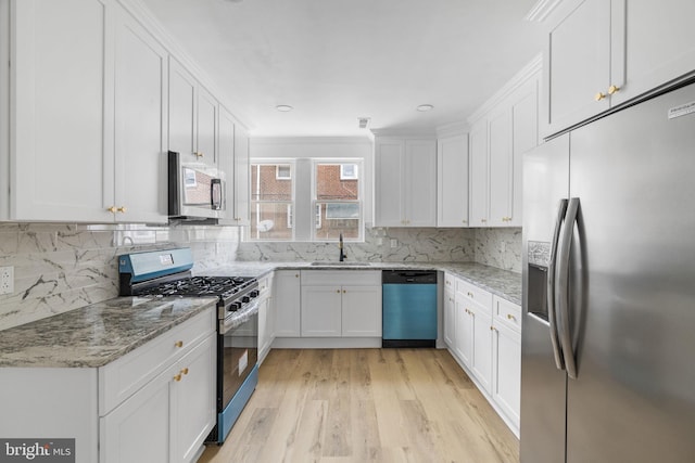 913 E Sanger St, Philadelphia, PA 19124 - kitchen featuring stainless steel appliances, light wood-style floors, white cabinetry, backsplash, and crown molding