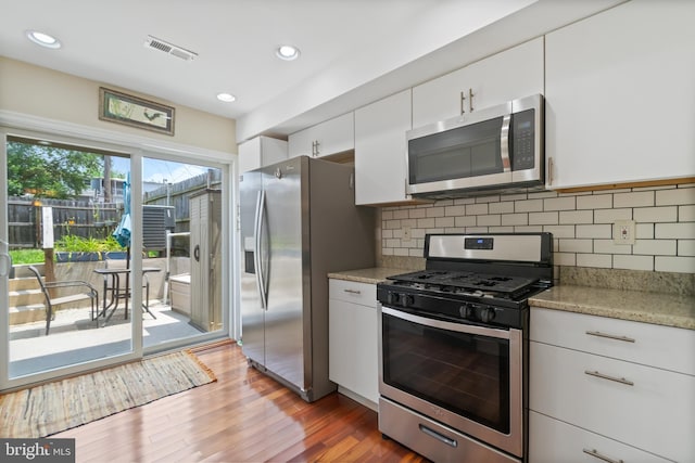 3343 Paine St, Baltimore, MD 21211 - kitchen featuring appliances with stainless steel finishes, white cabinetry, tasteful backsplash, wood finished floors, and light stone counters
