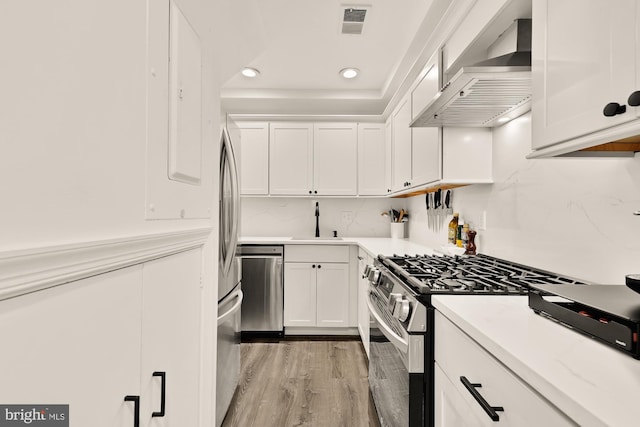 1811 19th St NW Unit 2, Washington, DC 20009 - kitchen with stainless steel appliances, custom exhaust hood, white cabinetry, light wood-type flooring, and light countertops