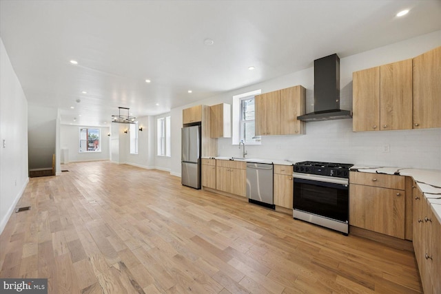 4063 Spring Garden St, Philadelphia, PA 19104 - kitchen featuring appliances with stainless steel finishes, wall chimney range hood, light wood-style floors, tasteful backsplash, and plenty of natural light