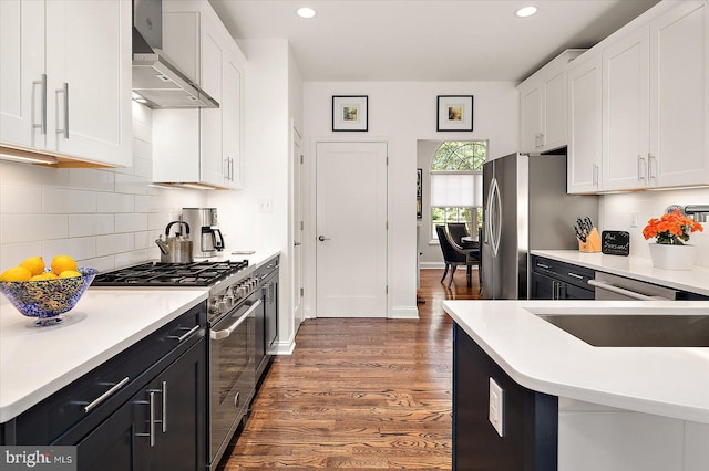112 W Shore Dr, Milton, DE 19968 - kitchen featuring appliances with stainless steel finishes, wall chimney exhaust hood, white cabinets, dark wood finished floors, and recessed lighting