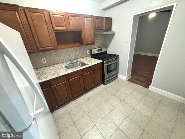 5803 Old Second St, Philadelphia, PA 19120 - kitchen featuring stainless steel gas stove, under cabinet range hood, backsplash, light tile patterned floors, and light stone countertops