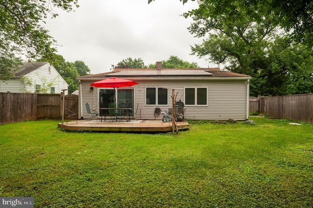 100 Garrett Rd, Glen Burnie, MD 21060 - rear view of house featuring a fenced backyard, a wooden deck, solar panels, and a chimney