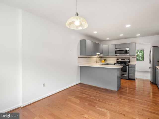 398 Lynetree Dr Unit 11-D, West Chester, PA 19380 - kitchen with stainless steel appliances, gray cabinets, a peninsula, light wood-style floors, and decorative backsplash