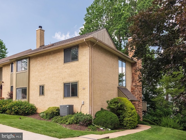 398 Lynetree Dr Unit 11-D, West Chester, PA 19380 - view of side of home with stucco siding, a chimney, and a lawn