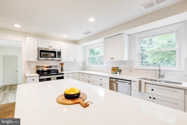 406 Christian Ln, Wallingford, PA 19086 - kitchen featuring appliances with stainless steel finishes, white cabinets, decorative backsplash, light countertops, and recessed lighting