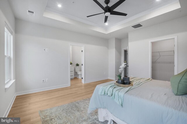 8109 Primrose Ln, Laurel, MD 20723 - bedroom featuring a tray ceiling, light wood-type flooring, recessed lighting, a walk in closet, and ensuite bathroom