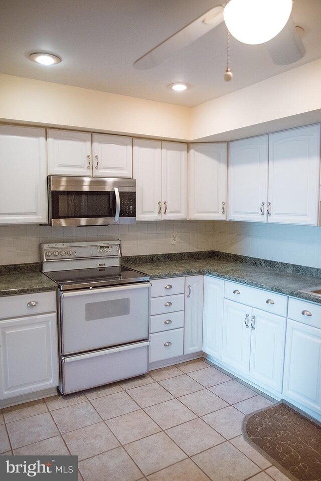 16 Stonehenge Cir Unit 16-5, Baltimore, MD 21208 - kitchen featuring stainless steel microwave, electric range, dark countertops, white cabinets, and backsplash