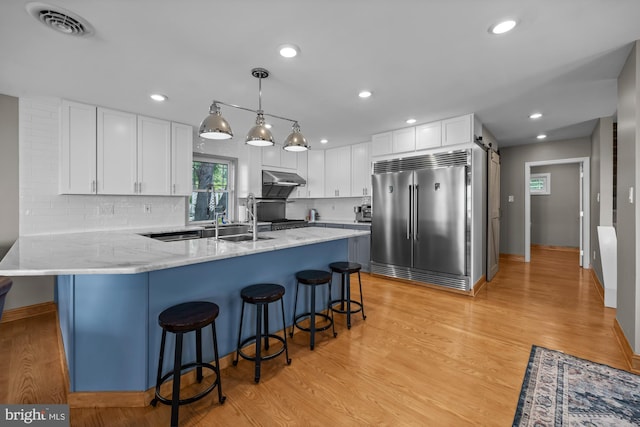 1 Risner Ave, Penns Grove, NJ 08069 - kitchen with stainless steel built in refrigerator, under cabinet range hood, white cabinetry, light stone counters, and light wood finished floors