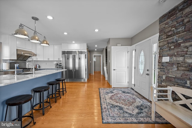 1 Risner Ave, Penns Grove, NJ 08069 - kitchen with built in fridge, white cabinetry, light stone countertops, light wood-type flooring, and under cabinet range hood