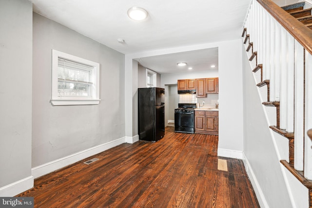 2006 N Mascher St, Philadelphia, PA 19122 - kitchen with freestanding refrigerator, gas range, dark wood-style flooring, brown cabinetry, and under cabinet range hood