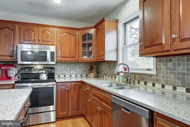2912 Weaver Rd, Lancaster, PA 17601 - kitchen with appliances with stainless steel finishes, decorative backsplash, glass insert cabinets, brown cabinets, and light stone countertops