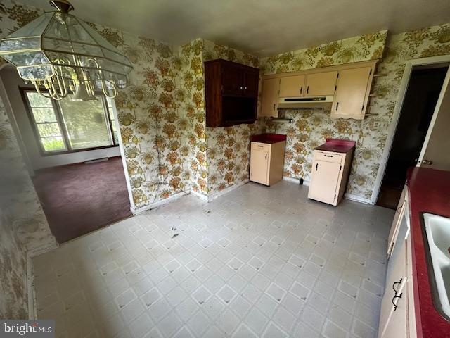 2304 Front Royal Pike, Winchester, VA 22602 - kitchen featuring wallpapered walls, under cabinet range hood, a chandelier, and tile patterned floors