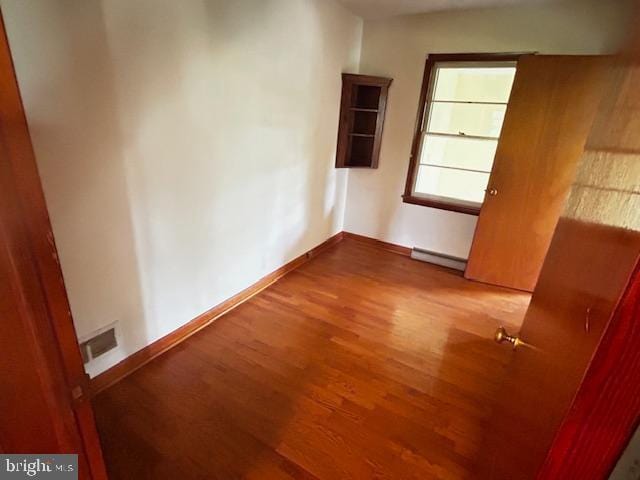 2304 Front Royal Pike, Winchester, VA 22602 - empty room with wood finished floors and a baseboard heating unit