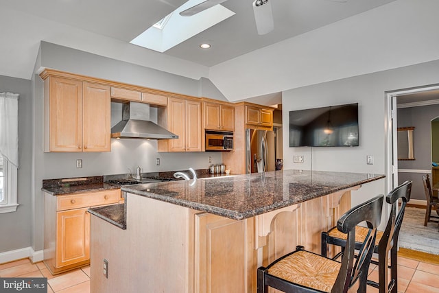 2413 Taylor Ave, Alexandria, VA 22302 - kitchen featuring wall chimney range hood, stainless steel appliances, light tile patterned floors, a breakfast bar area, and a skylight