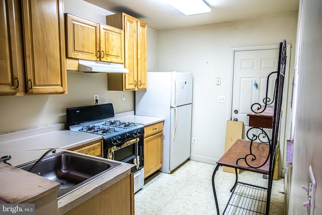 1504 Stricker, Druid, MD 21217 - kitchen featuring gas range, under cabinet range hood, freestanding refrigerator, light floors, and light countertops