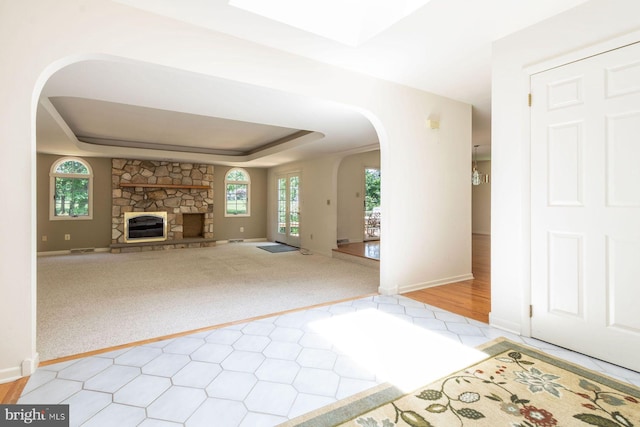 2381 Greensward S, Warrington, PA 18976 - unfurnished living room featuring arched walkways, a raised ceiling, a fireplace, a skylight, and carpet