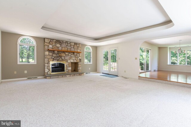 2381 Greensward S, Warrington, PA 18976 - unfurnished living room with a tray ceiling, a stone fireplace, carpet, and healthy amount of natural light