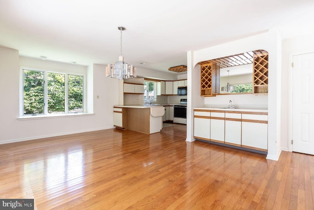 2381 Greensward S, Warrington, PA 18976 - kitchen with white stove, light wood-type flooring, black microwave, light countertops, and hanging light fixtures