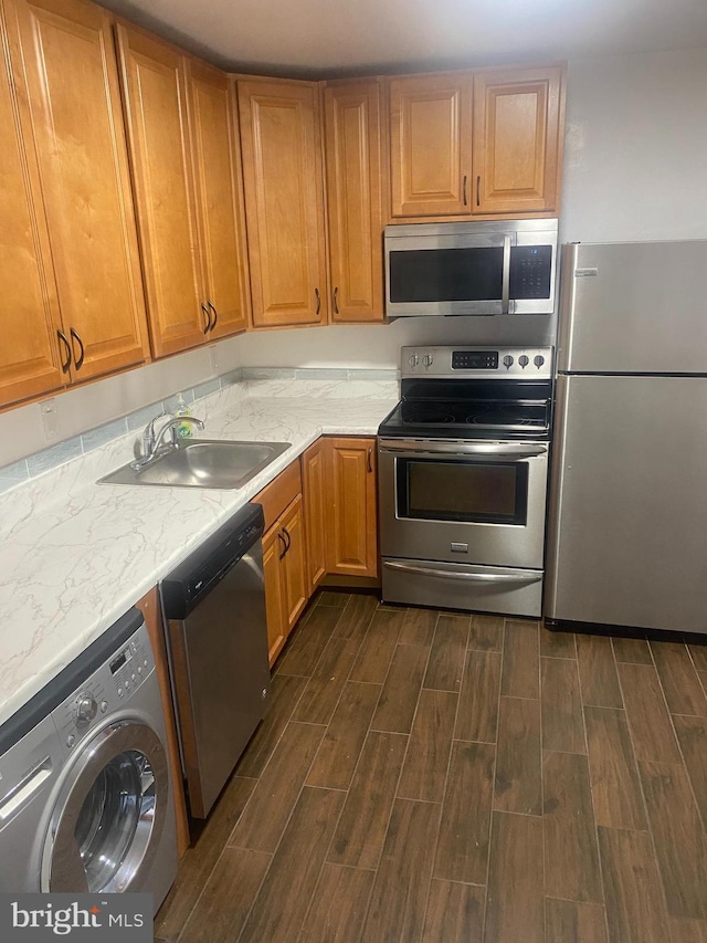 11393 Laurelwalk Dr Unit B-141, Laurel, MD 20708 - kitchen featuring appliances with stainless steel finishes, washer / clothes dryer, dark wood-style flooring, light stone counters, and brown cabinets