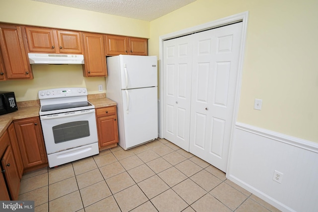 120 Ridgefield Ln, Fruitland, MD 21826 - kitchen with white appliances, under cabinet range hood, a wainscoted wall, light countertops, and a textured ceiling