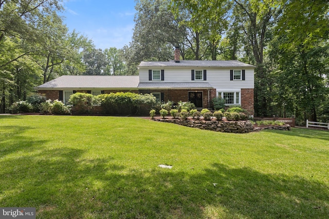 3851 Fawn Ln, White Plains, MD 20695 - traditional-style house with brick siding, a front lawn, a chimney, and view of wooded area