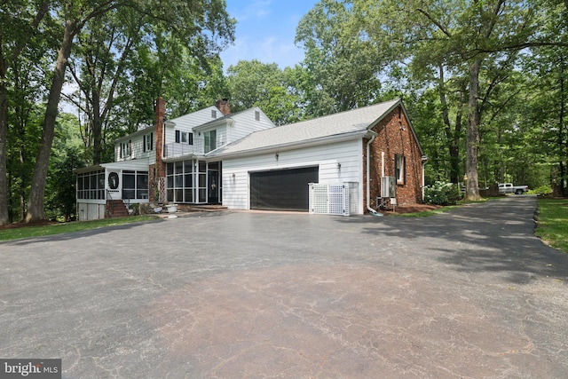 3851 Fawn Ln, White Plains, MD 20695 - view of front of house featuring a sunroom, a garage, driveway, brick siding, and a chimney