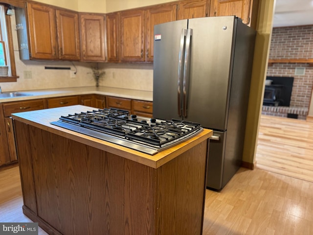 400 27th St, Huntingdon, PA 16652 - kitchen featuring appliances with stainless steel finishes, light wood finished floors, brown cabinetry, a kitchen island, and light countertops